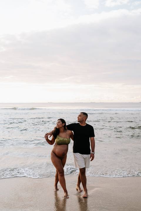 Foto do casal em pé na beira da água.'