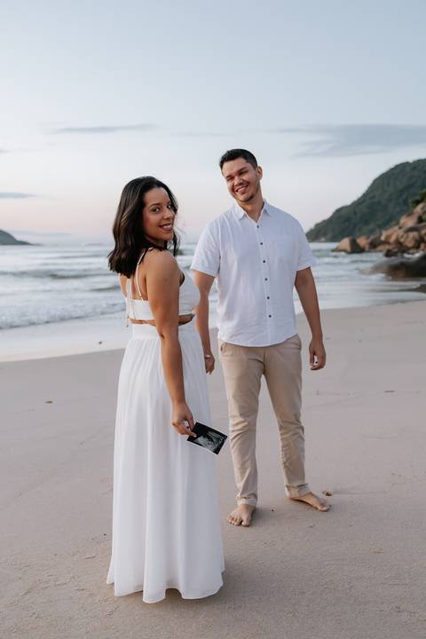 Foto do casal caminhando na areia com o ultrassom em destaque.'