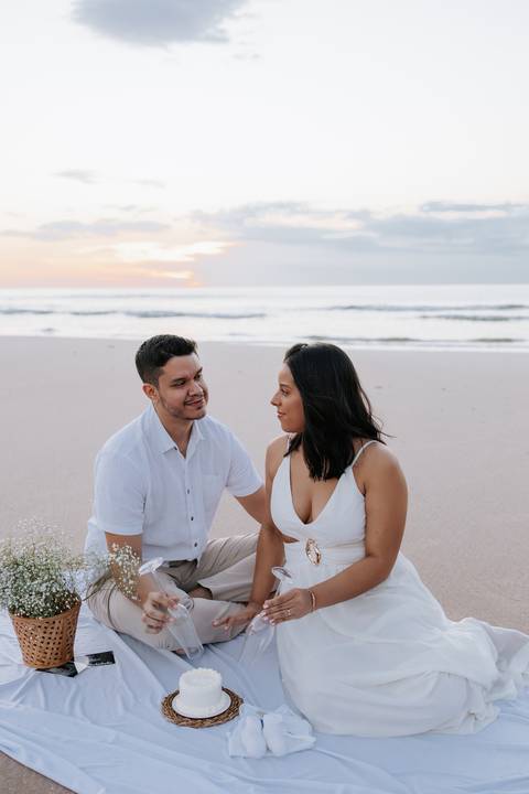 Foto do casal trocando olhares ansiosos ao lado do bolo de revelação.'