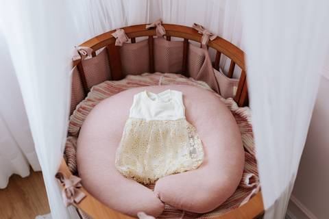 Foto em ângulo superior do berço com a primeira roupinha do bebê.'
