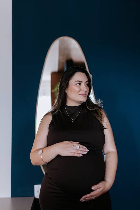 Foto de perfil da gestante sorrindo em ensaio documental em casa.'