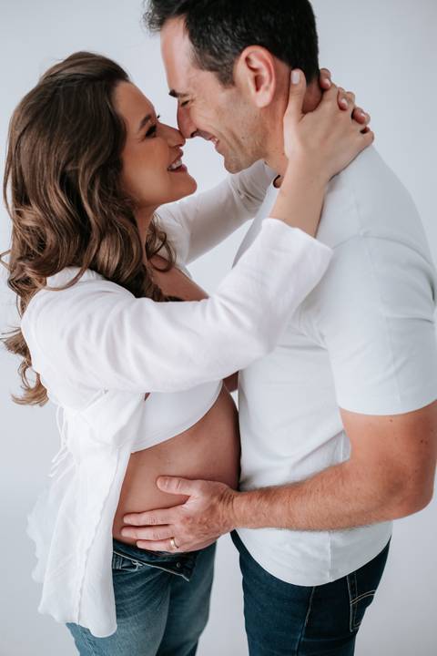 Foto aproximada do casal abraçado com destaque para a barriga de grávida.'