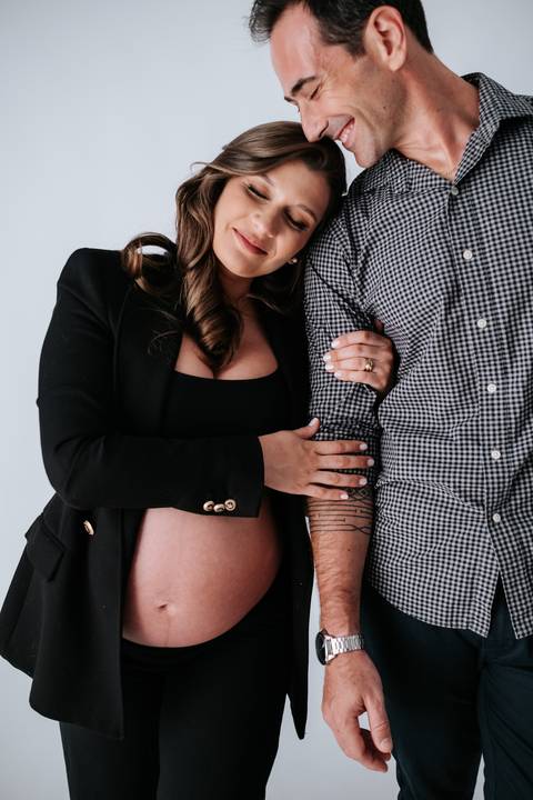 Foto do casal abraçado com foco na conexão e na espera pelo bebê.'