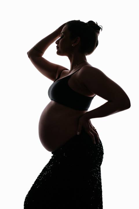 Foto da silhueta de perfil da gestante destacando a curva da barriga em fundo branco.'