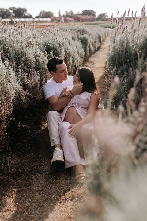 Foto do casal sentado entre as flores em momento de conexão e afeto.'