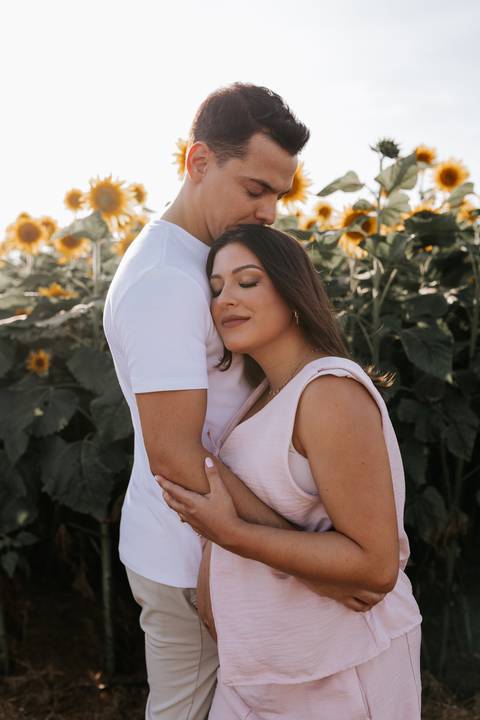 Foto da gestante encostando o rosto no peito do parceiro com olhos fechados.'