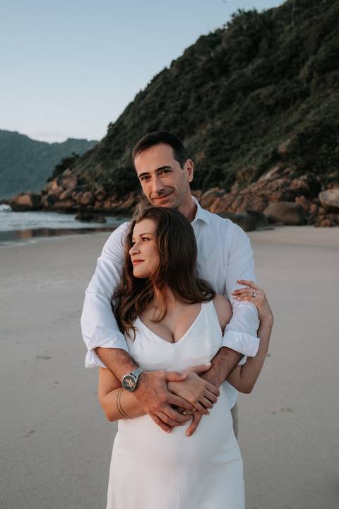 Foto do casal posando na areia com foco na expressão de felicidade.'