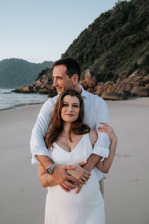 Foto aproximada do casal abraçado durante o ensaio gestante externo.'