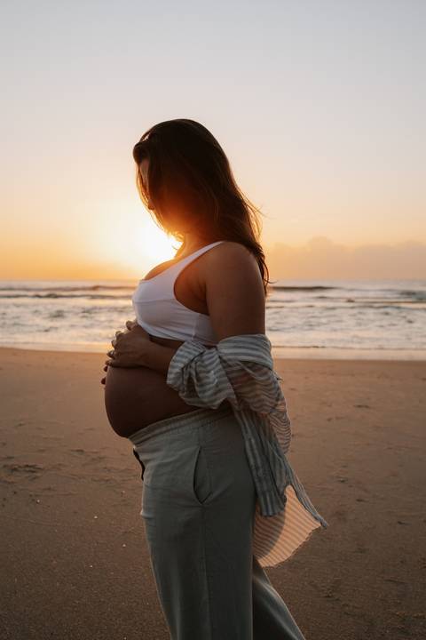 Foto da silhueta da barriga da gestante contra a luz forte do nascer do sol.'