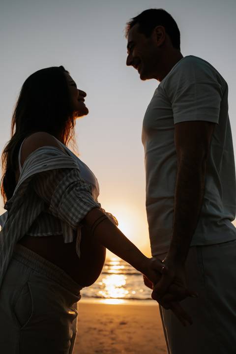 Foto aproximada da silhueta do casal focando na conexão e no perfil da barriga.'
