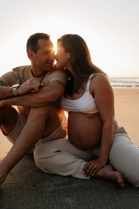 Foto aproximada do casal sentado na areia.'