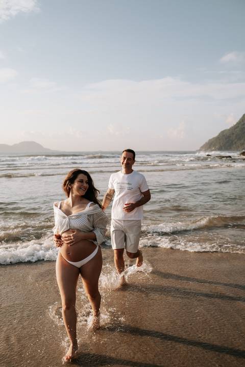 Foto do casal de mãos dadas com a imensidão do mar ao fundo.'