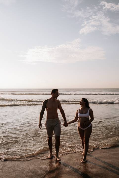 Foto da silhueta do casal caminhando em direção ao mar.'