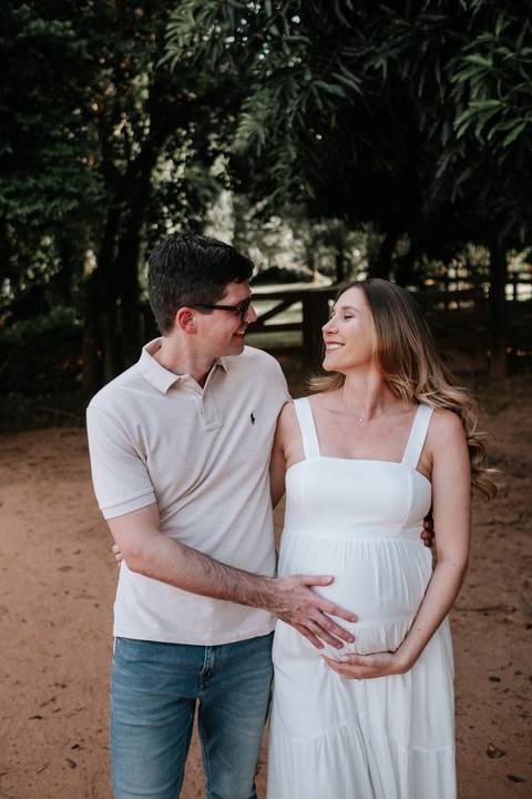 Foto do casal trocando olhares e sorrisos em primeiro plano.'