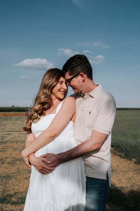 Foto do casal encostando os rostos em momento de carinho no campo.'