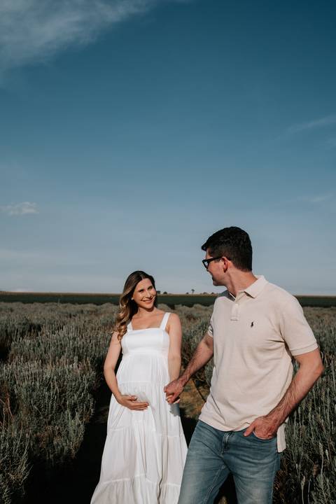 Foto do casal trocando olhares apaixonados no cenário rural.'