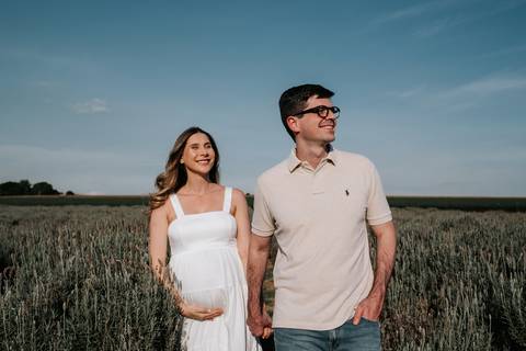 Foto do casal caminhando na plantação com horizonte ao fundo.'