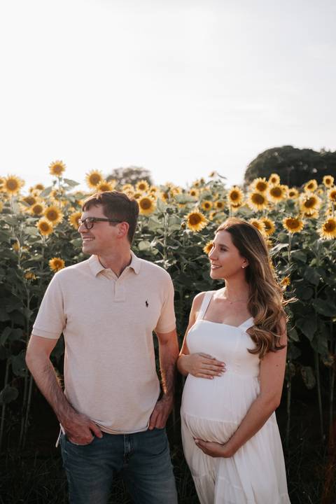 Foto do casal trocando olhares em frente à plantação.'