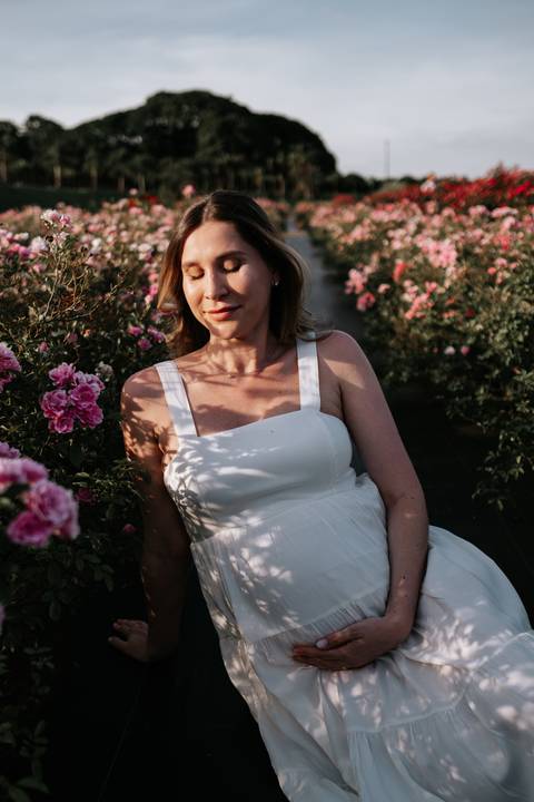 Foto aproximada da gestante sorrindo em meio à natureza.'