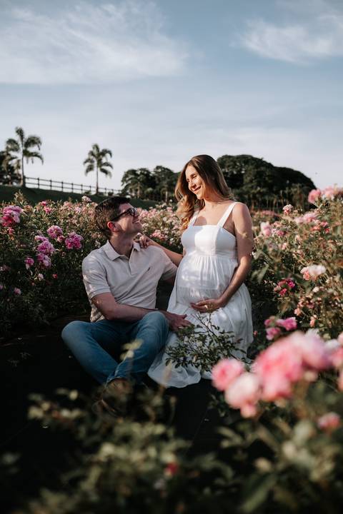 Foto do casal trocando olhares sentados no jardim.'