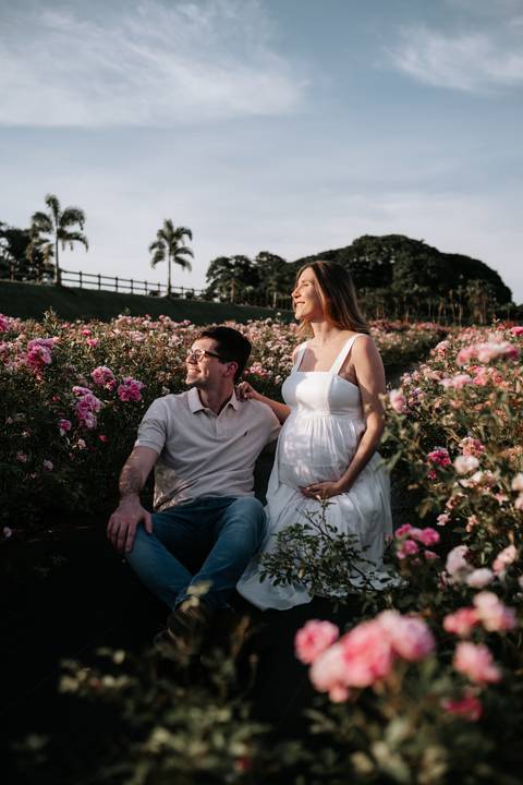 Foto do casal sorridente posando no campo de flores.'