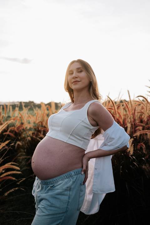 Foto da gestante contemplando o horizonte no entardecer.'