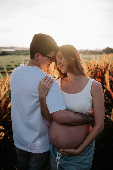 Foto aproximada do casal em momento romântico no campo aberto.'