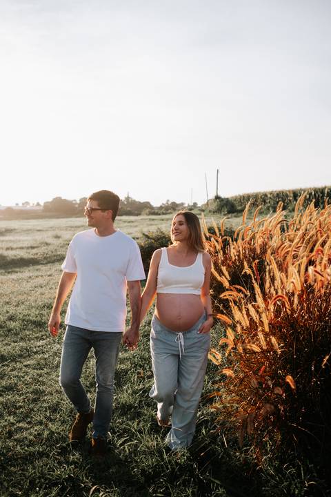 Foto do casal de mãos dadas caminhando no gramado aberto.'