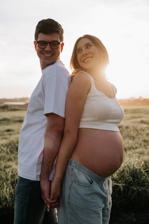 Foto aproximada do casal em silhueta lateral no campo.'