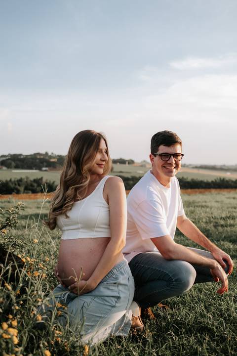 Foto do casal sentado no gramado trocando olhares.'
