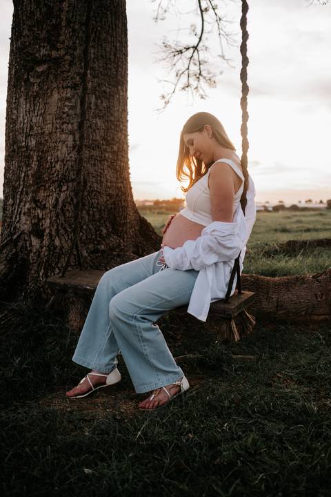 Foto de perfil da gestante sentada no balanço na 