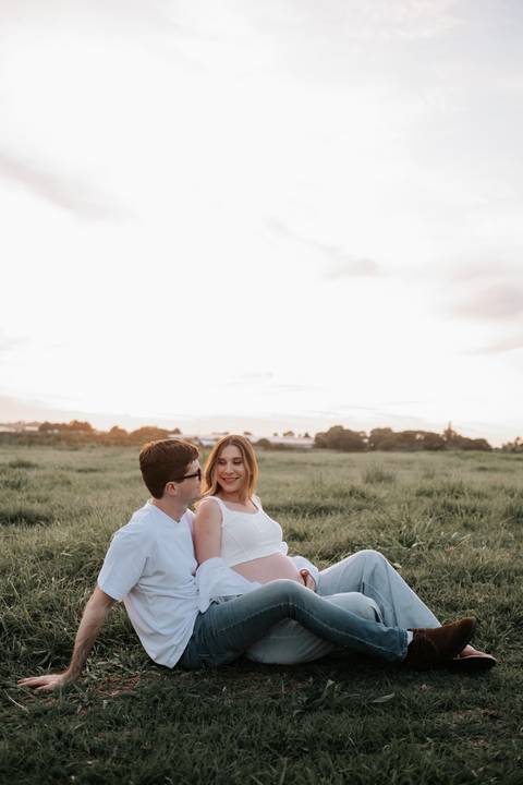 Foto do casal sentado na grama em momento de conexão.'