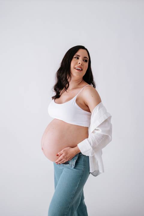 Foto aproximada da gestante destacando a barriga em estilo minimalista.'