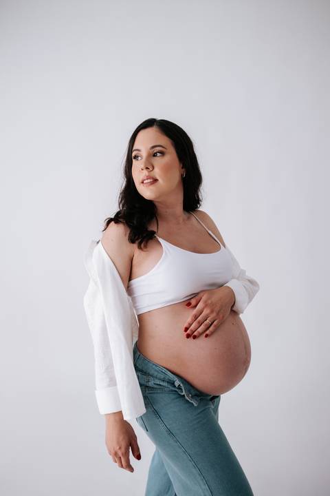 Foto da gestante posando com olhar sereno em ensaio de estúdio.'