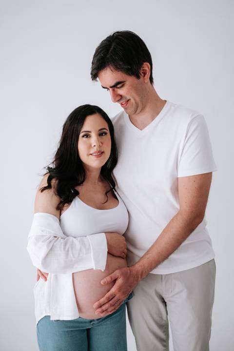 Foto do casal sorrindo e olhando para a câmera em plano médio.'