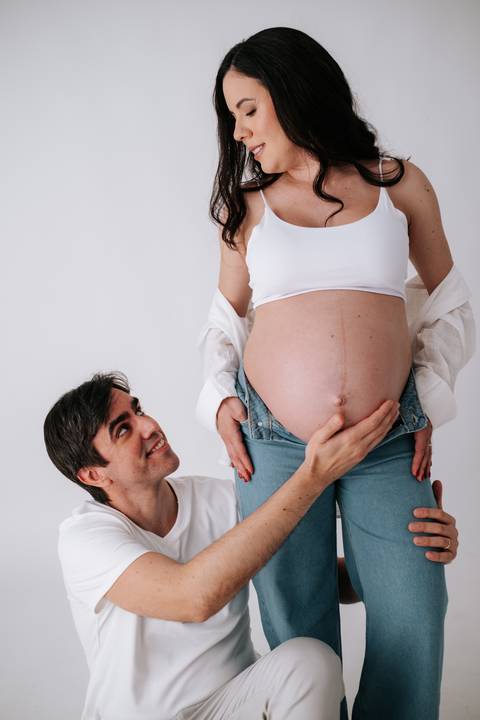 Foto aproximada do pai olhando com carinho para a barriga.'