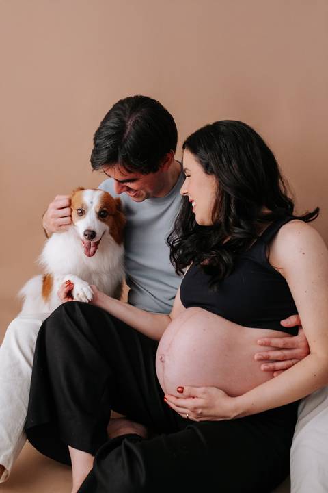 Foto do casal brincando com o cão de estimação com look preto.'