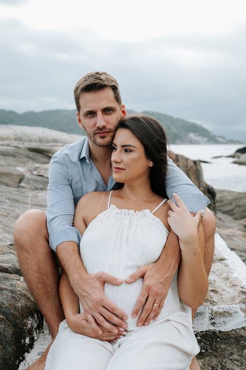 Foto do casal sentado nas rochas em momento de conexão.'
