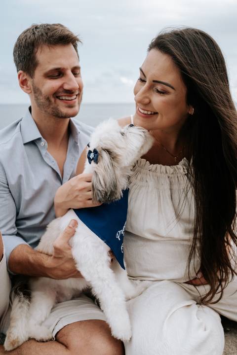 Foto aproximada do casal acariciando o cão durante o ensaio.'