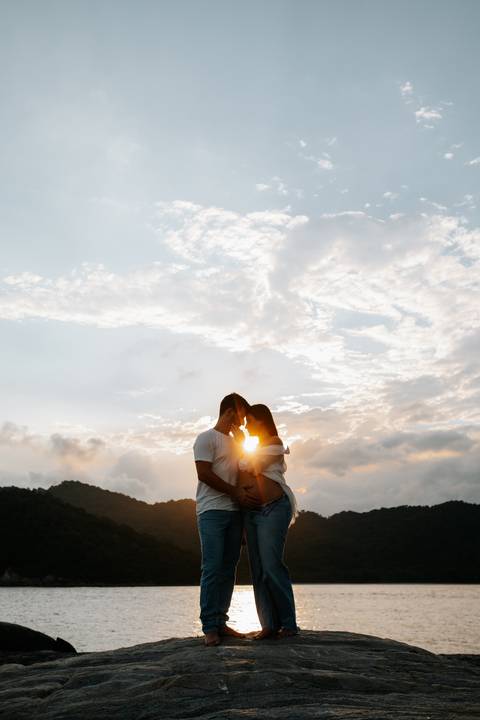 Foto da silhueta do casal se beijando contra o sol poente.'