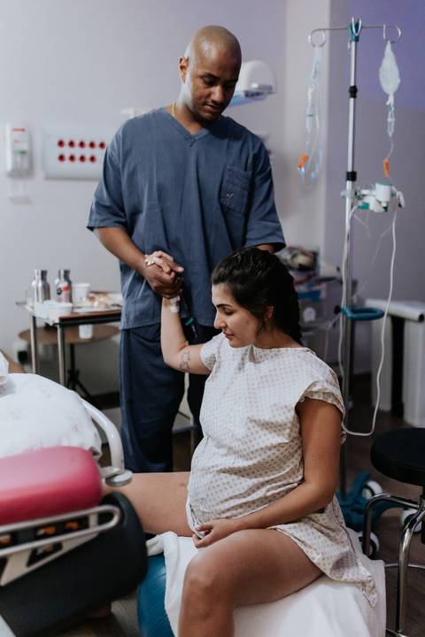Foto da mãe concentrada durante o processo de parto no hospital.'