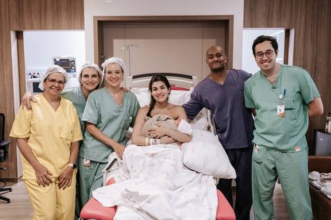 Foto da equipe médica reunida com a família após o nascimento.'