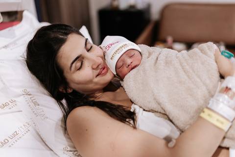 Foto da mãe com a bebê no colo logo após o nascimento.'