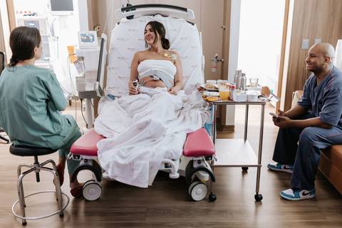 Foto em plano aberto do quarto hospitalar com a família e equipe.'