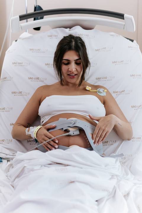 Foto da gestante sentada na cama.'