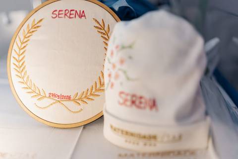 Foto em detalhe do enxoval personalizado e touca da maternidade.'