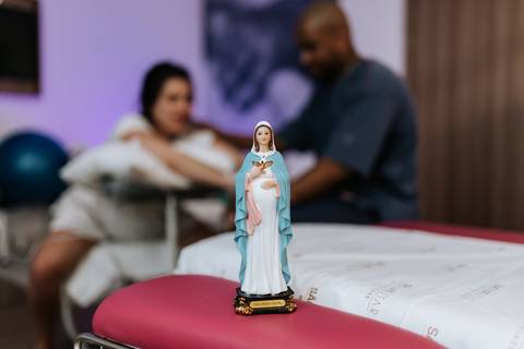 Foto do casal em segundo plano e imagem religiosa em destaque. '