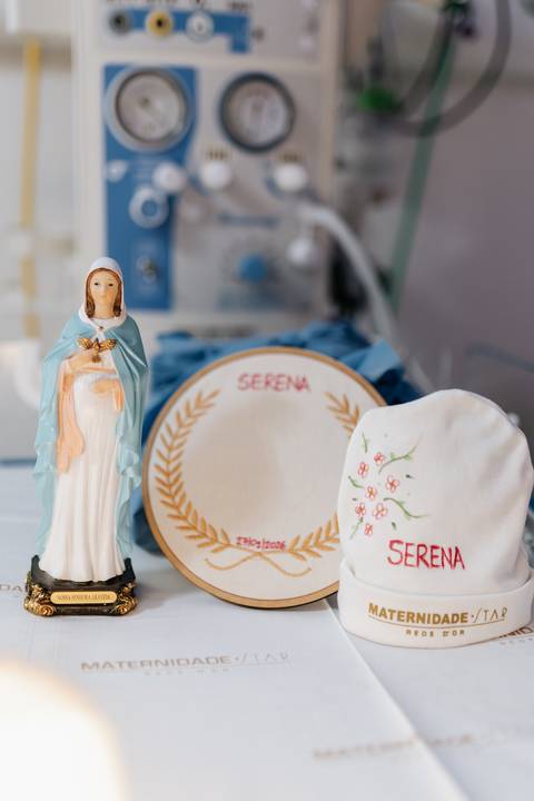 Foto em detalhe do enxoval personalizado e imagem da santa.'