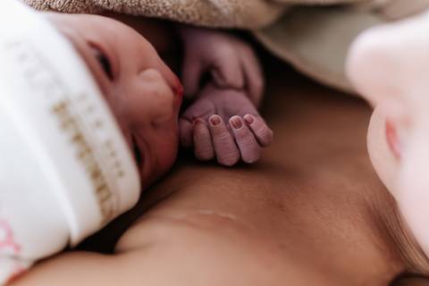 Foto aproximada da bebê em contato pele a pele com a mãe.'