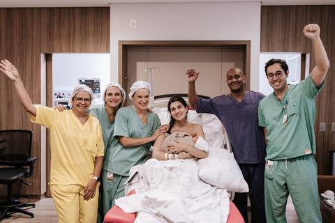 Foto da família reunida com a equipe médica celebrando a vida.'